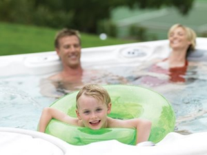boy in green inner tube in hot tub with parents