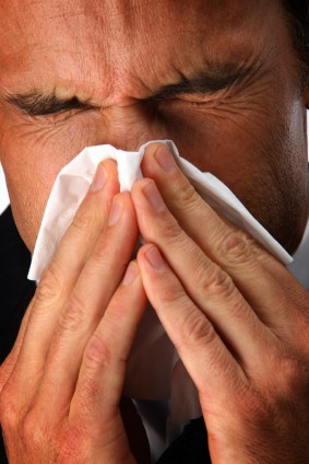 Man with a cold sneezing into a tissue