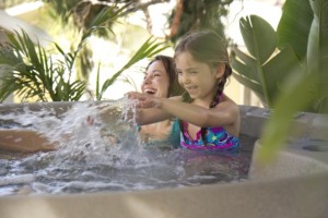smiling woman and little girl splashing in hot tub