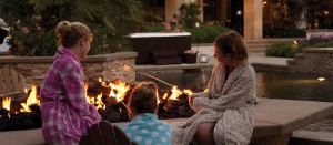 children roasting marshmallows in fire pit, parents in hot tub overseeing