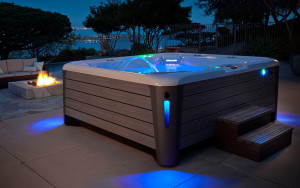 illuminated hot tub in patio with fire pit at dusk