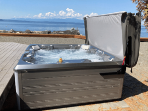 A HotSpring Pulse hot tub in an Olympic Hot Tub customer's yard in Freeland, with a body of water visible in the background.